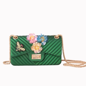 Detail of green jelly bag with V-quilted texture, floral sequins and bee embroidery