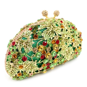 Close-up of golden hollow leaf metal frame with colorful rhinestones on green clutch