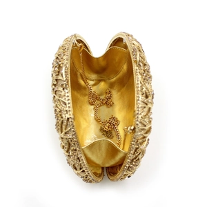 Detail of open gold rhinestone clutch with hollow metal pattern and interior chain strap