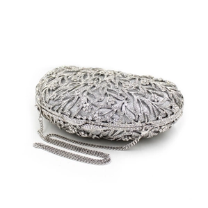 Macro detail of silver hollow-out dinner clutch with sparkling rhinestones and metal chain