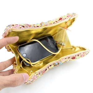 Luxurious gold evening bag with colorful rhinestones showing internal phone storage capacity
