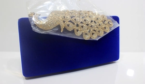 Detailansicht des Pfauen-Strass-Ornaments auf der königsblauen Samt-Abendtasche