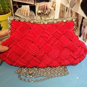 Detail of red woven evening clutch bag featuring rhinestone gold frame and metal chain