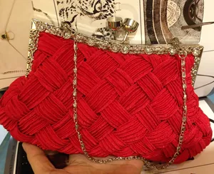 Detail of red pleated satin bridal clutch featuring rhinestone flowers and metal chain