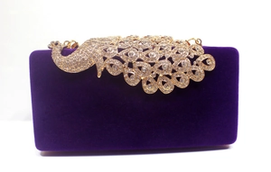 Detailsicht der lila Samt-Abendtasche mit einem kristallbesetzten goldenen Pfau-Dekor