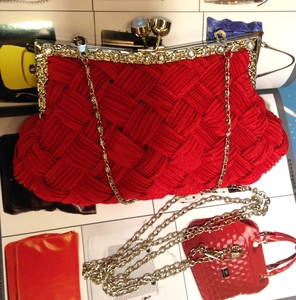 Macro shot of red woven satin clutch with floral rhinestone clasp and gold chain strap