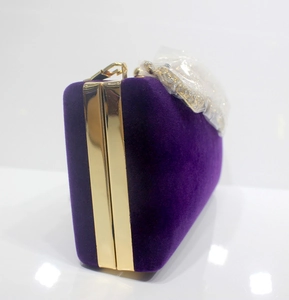 Makro-Detail der lila Samt-Clutch mit goldenem Metallrahmen und Strassverschluss