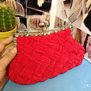 Close-up of red woven bridal clutch featuring a crystal-embellished silver metal frame
