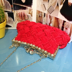 Close-up of red woven evening clutch with rhinestone silver frame and metal chain strap
