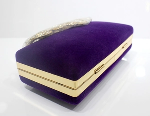Makro-Detail der lila Samt-Abendtasche mit goldenem Kristallverschluss und Metallrahmen