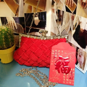 Detailed close-up of red woven clutch with vintage metal clasp and elegant chain strap