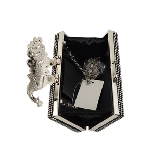 Detail view of crystal evening clutch with floral clasp, silver chain, and black lining