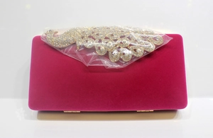 Makro-Detail der magentafarbenen Samt-Abendtasche mit Pfau-Strass-Verzierung