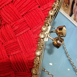 Detailed close-up of red woven satin evening clutch with gold rhinestone-studded clasp