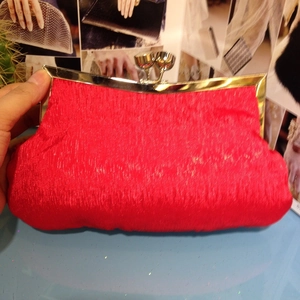 Detail of red satin evening clutch bag with gold metal frame and ball clasp closure