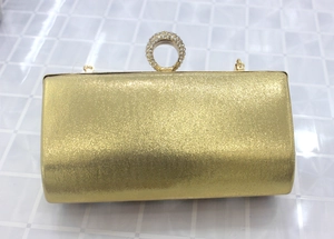 Close-up of golden glitter evening clutch with crystal-encrusted ring clasp and chain