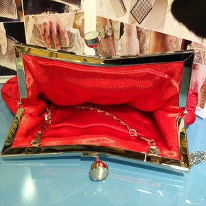 Detail view of red pleated evening clutch interior with satin lining and chain strap
