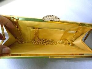 Detailed view of gold rhinestone clutch interior with satin lining and metal chain
