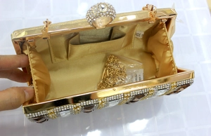 Detail of gold evening clutch bag with rhinestones, satin lining and chain strap