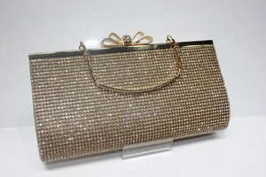 Detail of golden evening clutch featuring high-density rhinestones and bow-shaped clasp