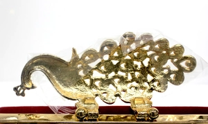 Detailansicht des goldenen Pfauen-Metallverschlusses an der luxuriösen roten Samt-Abendtasche