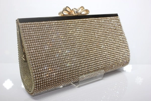 Close-up of golden evening clutch featuring rhinestone inlay and bow-shaped clasp