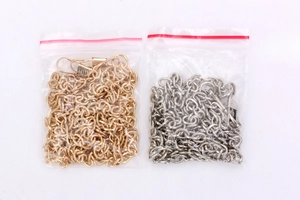 Detail of silver and gold metal tassel chains with lobster clasps in clear packaging