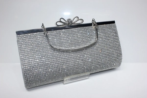 Macro view of silver evening clutch bag with sparkling rhinestones and crystal bow clasp