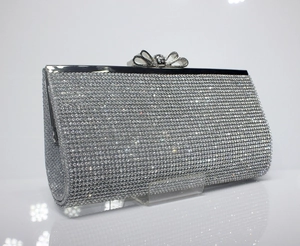 Detailed view of silver rhinestone clutch with luxury crystal bow clasp and mirror reflection