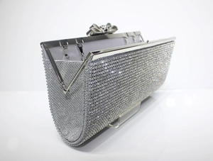 Detailed view of silver rhinestone evening clutch bag with crystal bow clasp and metal frame