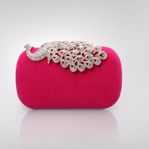 Close-up of a peacock-shaped crystal embellishment on a hot pink velvet evening clutch
