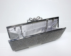 Close-up of silver rhinestone clutch with bow clasp and grey satin interior lining