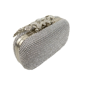 Macro shot of silver crystal clutch bag with leaf shaped diamond flower clasp detail