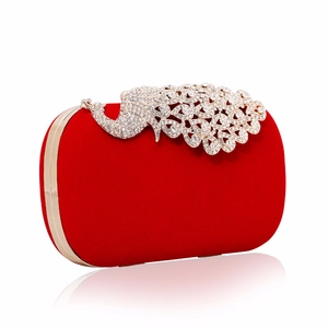 Detailed close-up of a red velvet evening clutch featuring a crystal peacock clasp