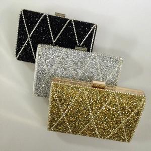 Three sequined hardcase evening clutches in black, silver, and gold with diamond patterns