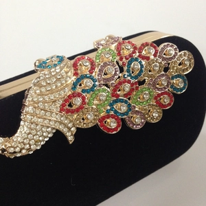 Close-up of colorful crystal peacock clasp on luxury black velvet evening clutch bag