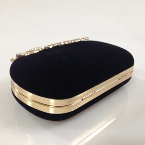 Close-up of black velvet evening clutch with gold metal frame and colorful crystals