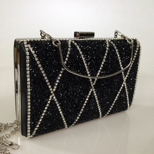 Macro detail of black evening clutch with silver rhinestone geometric patterns and chain