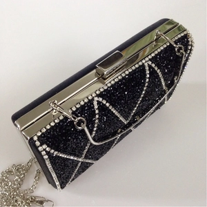 Detail of luxury black evening clutch with white rhinestone patterns and silver chain