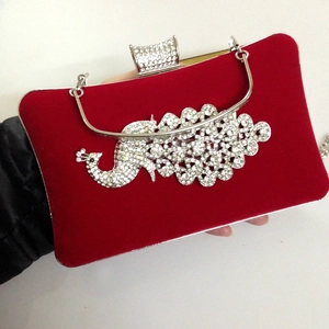 Detail of red velvet evening clutch featuring a luxury rhinestone peacock and metal clasp