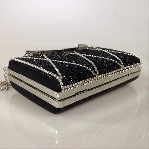 Detail of luxury black clutch bag with silver rhinestone diamond grid pattern and chain
