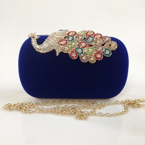 Detail view of royal blue velvet evening bag with colorful rhinestone peacock closure
