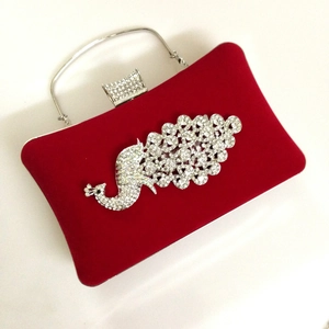 Detailed close-up of red velvet evening bag with sparkling crystal peacock decoration