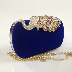 Detail of royal blue velvet evening bag with ornate colorful peacock rhinestone clasp