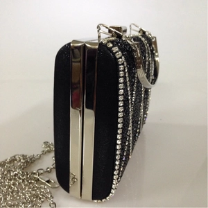 Detail of black satin evening clutch bag with vertical silver rhinestones and chain