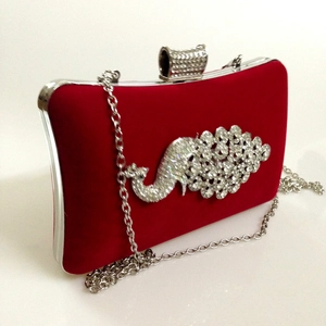 Detail view of red velvet evening clutch with silver chain and peacock rhinestone design