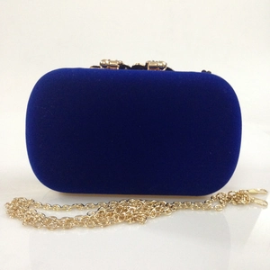 Detail of navy blue velvet evening clutch with gold ball clasp and metal chain strap