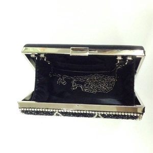 Detail of luxurious black evening clutch interior with silver chain strap and satin lining