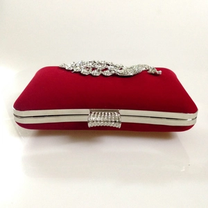 Detailed view of red velvet evening clutch with sparkling peacock rhinestone embellishment