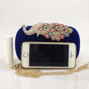 Detail of royal blue velvet evening clutch with colorful rhinestone peacock and gold chain